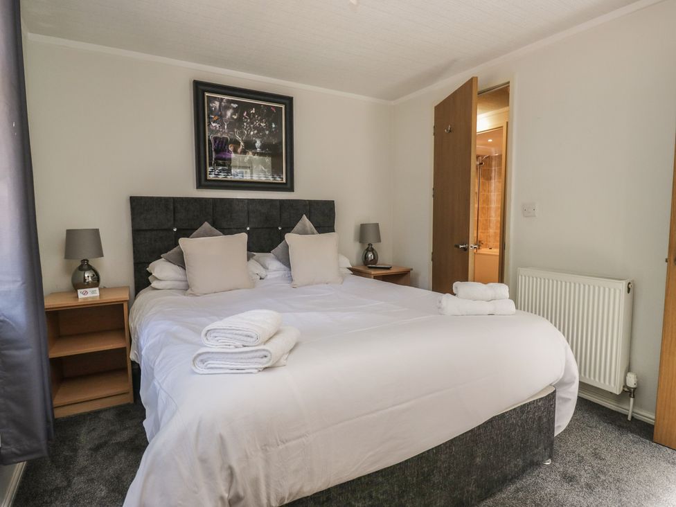 A bedroom with a bed and bedside table at Treetops, Beech Hill 13, Fallbarrow Park near Bowness-On-Windermere