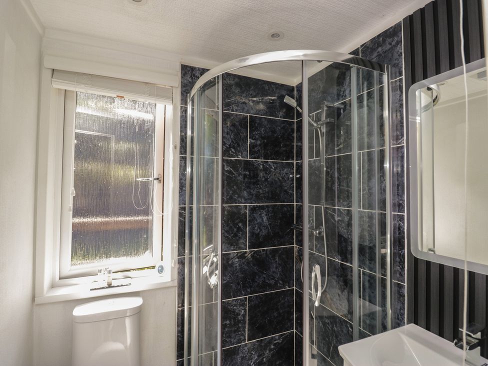 A bathroom with a shower, toilet, sink, and window at Treetops Beech Hill 13 ,Fallbarrow Park near Bowness-On-Windermere