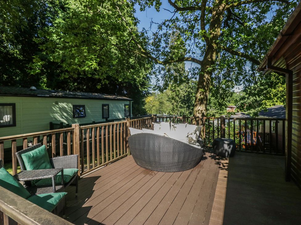A decking area with seating and trees at Treetops Beech Hill 13, Fallbarrow Park near Bowness-On-Windermere
