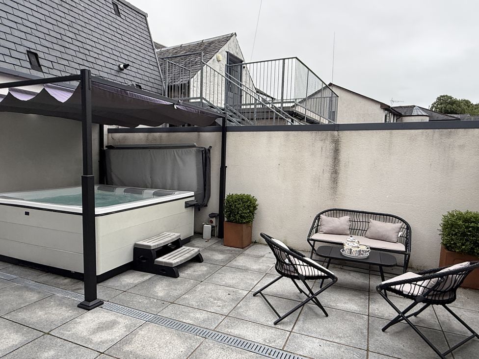 An outdoor area with a hot tub and seating at Shepherdess Cottage in Moffat