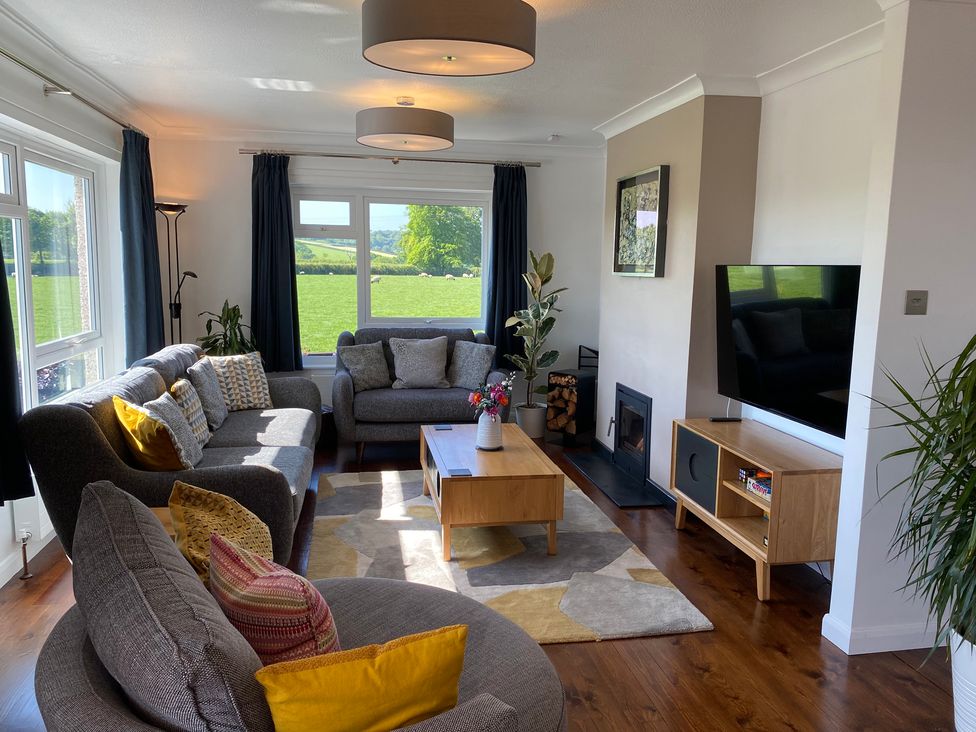 A living room with gray sofas a wooden coffee table a television and a fireplace at Ashlea in Launceston