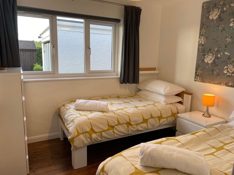 A bedroom with two single beds each with yellow and white bedding a chest of drawers and a bedside table with a lamp at Ashlea in Launceston