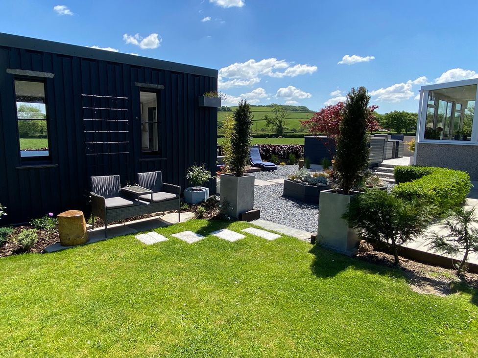 An outdoor garden area with lawn chairs plants and a lawn at Ashlea in Launceston