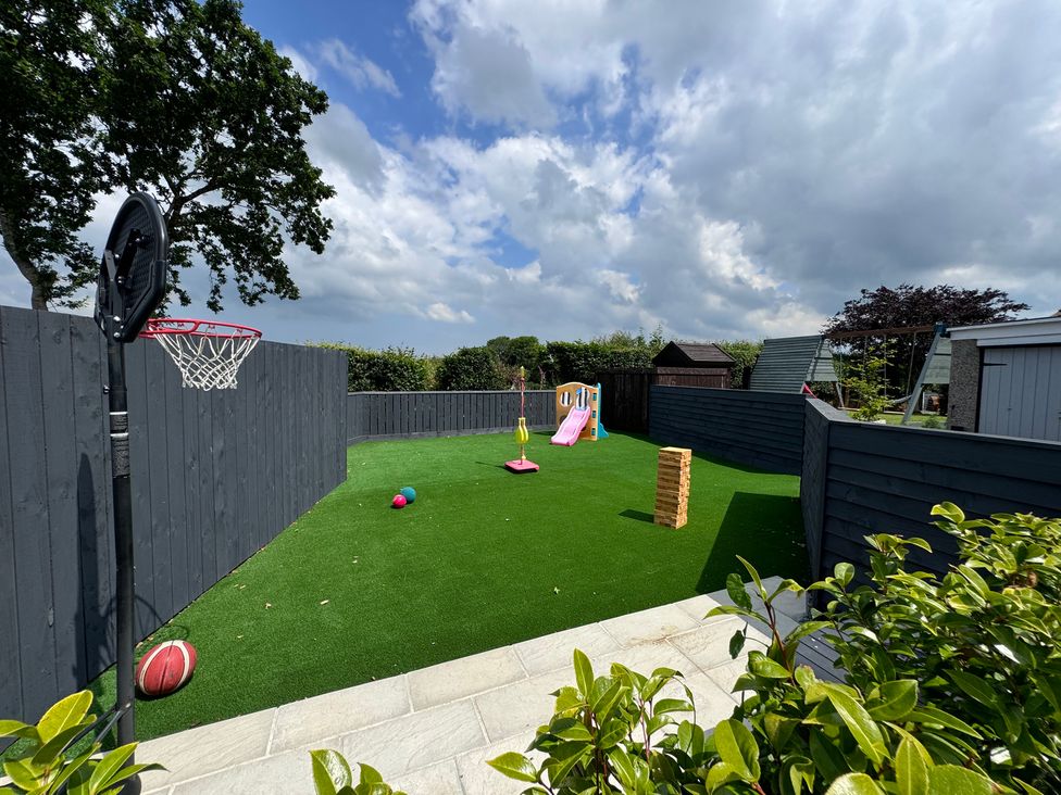 A backyard with artificial grass basketball hoop children's slide and swing set at Ashlea in Launceston