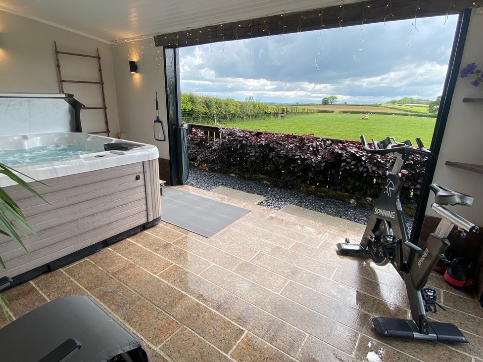 An indoor space with a hot tub and spinning exercise bike opening to a view of green fields at Ashlea in Launceston