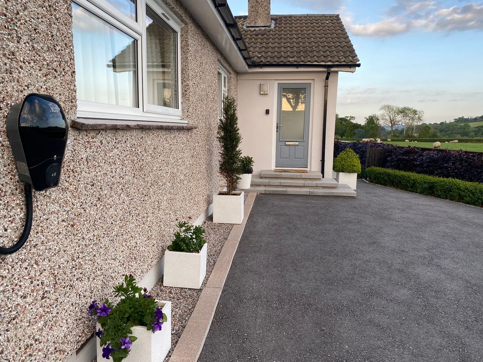 A house entrance with potted plants along the wall and a gray door at Ashlea in Launceston