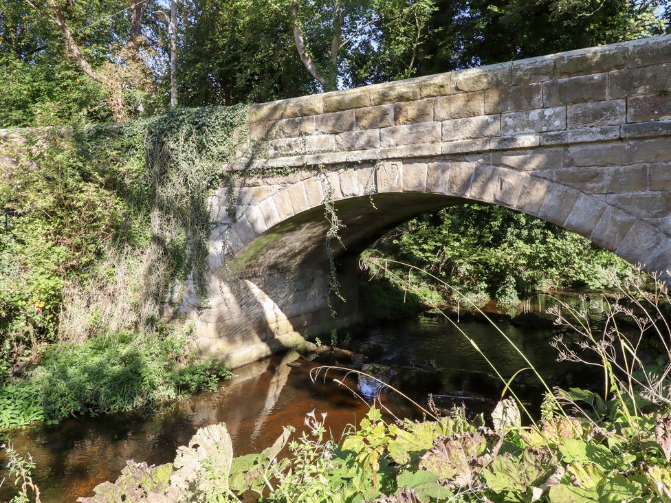 A stone bridge over a stream surrounded by trees at Pippin in Lucker