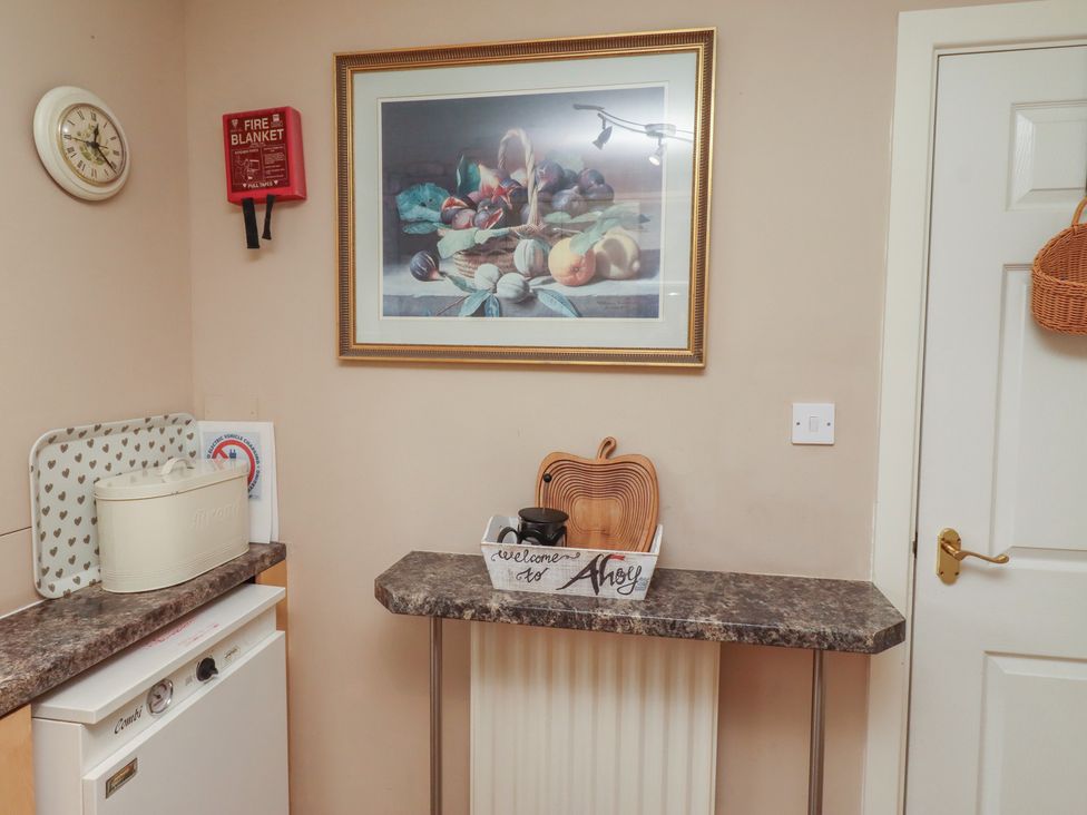 A kitchen with a clock, baking dish, and welcome sign at Ahoy in Seahouses