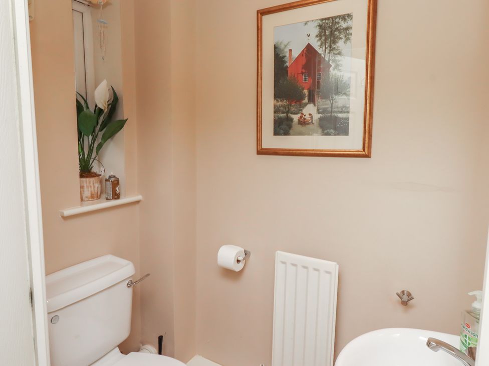 A bathroom with a toilet, wash basin, and wall art at Ahoy, Seahouses