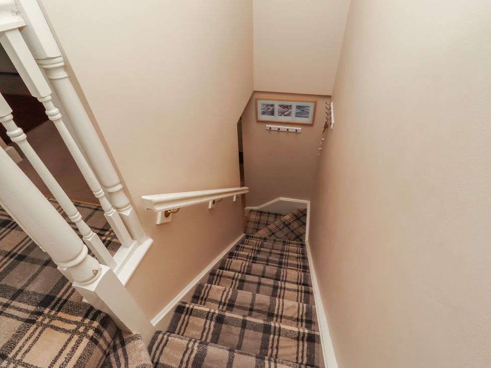 A staircase with a handrail and pictures in the stairway at Ahoy in Seahouses