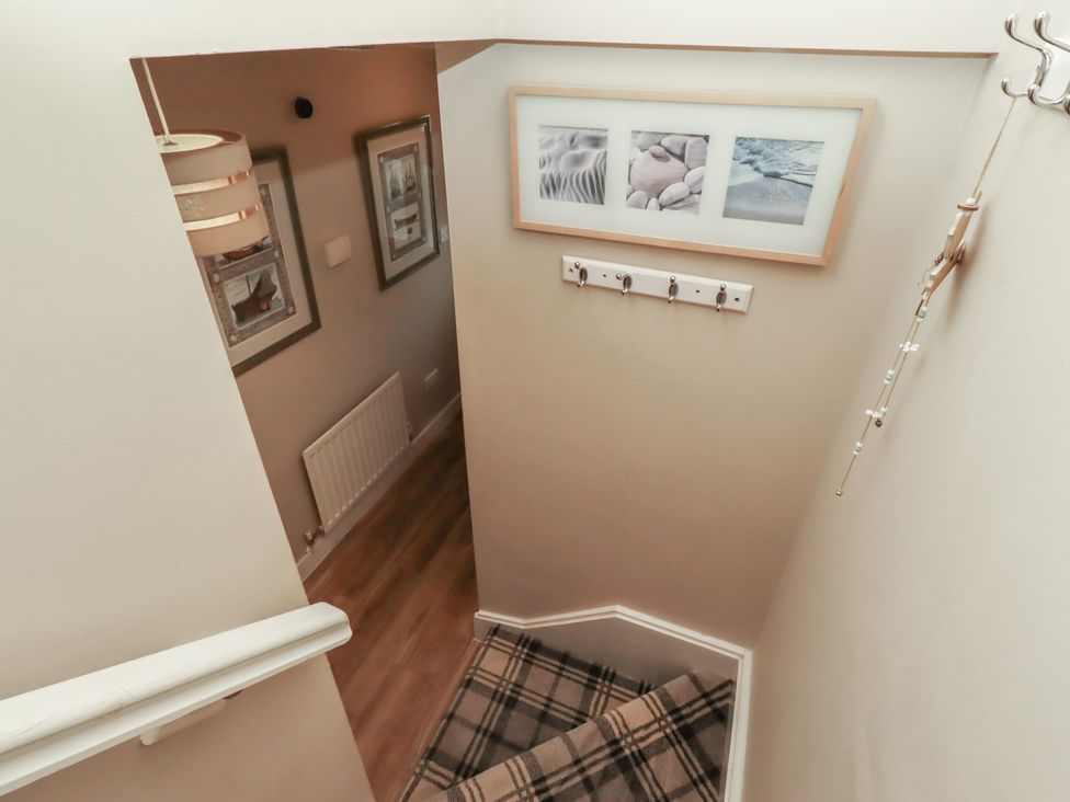 A staircase with wall art and hooks at Ahoy in Seahouses