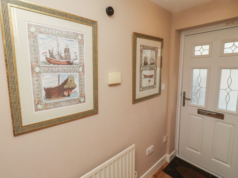 A hallway with framed maritime art and a door at Ahoy in Seahouses