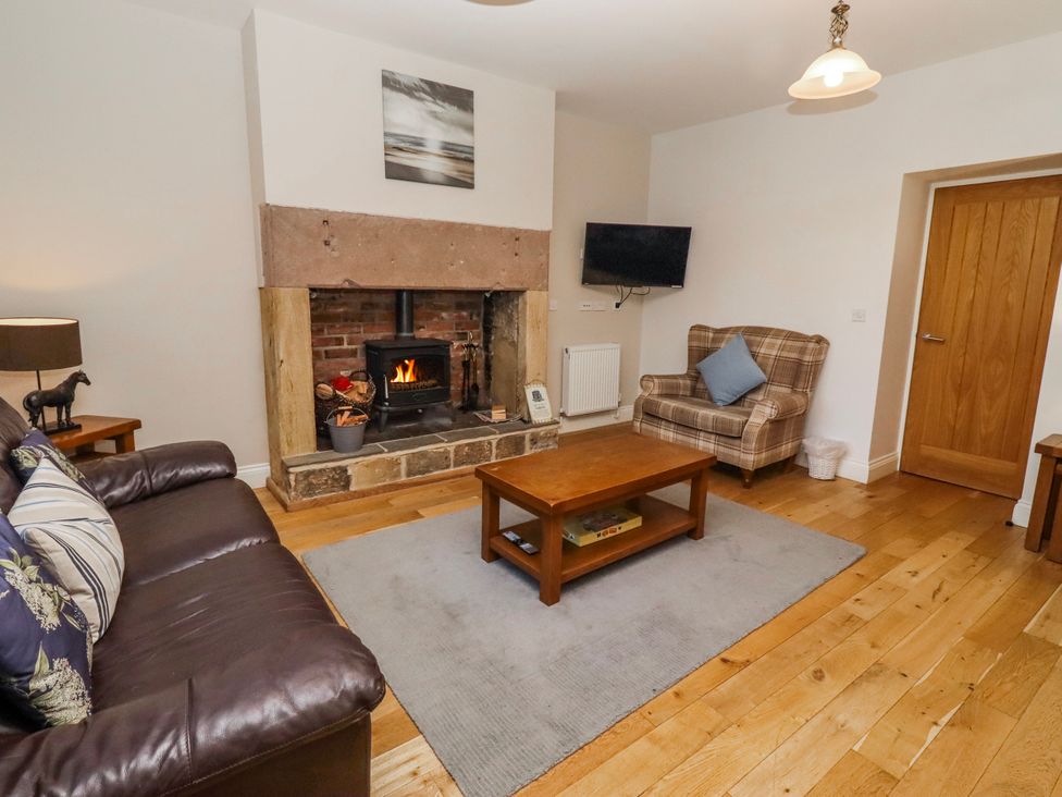 A living room with a fireplace and sofa at Bramley in Lucker