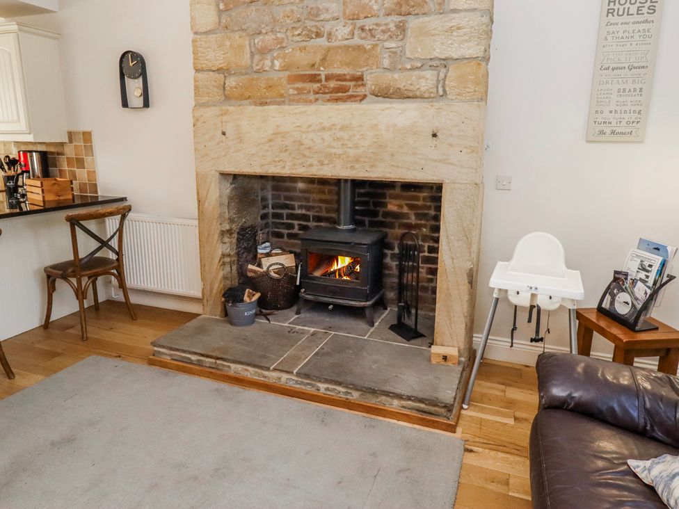 A living room with a fireplace and high chair at Bramley in Lucker