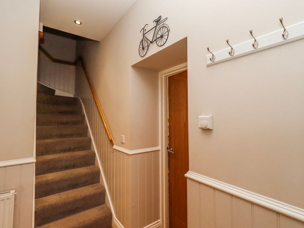 A hallway with stairs and coat hooks at Bramley in Lucker