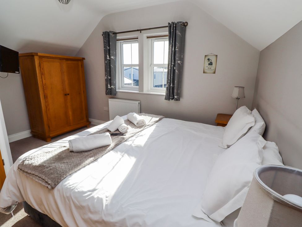 A bedroom with a bed, wardrobe, and windows at Bramley in Lucker