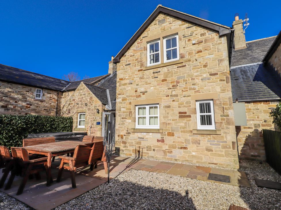 An outdoor area with a stone house and seating at Bramley in Lucker