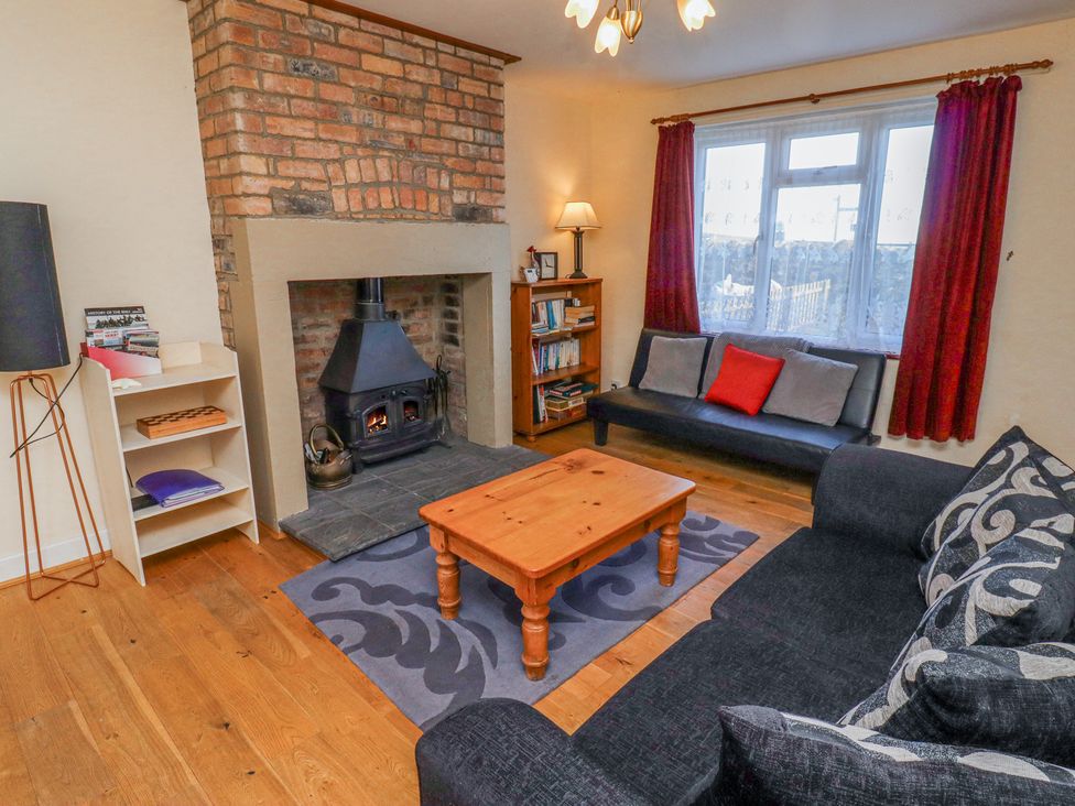 A living room with a wood burning stove brick fireplace wooden coffee table and two sofas at St Marys Cottages No1 in Low Newton-by-the-Sea