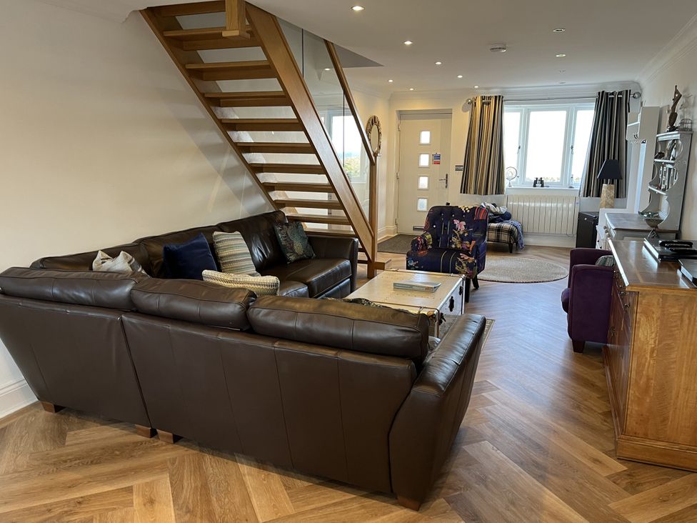 A living room with a sofa and staircases at Farne Cottage in Beadnell