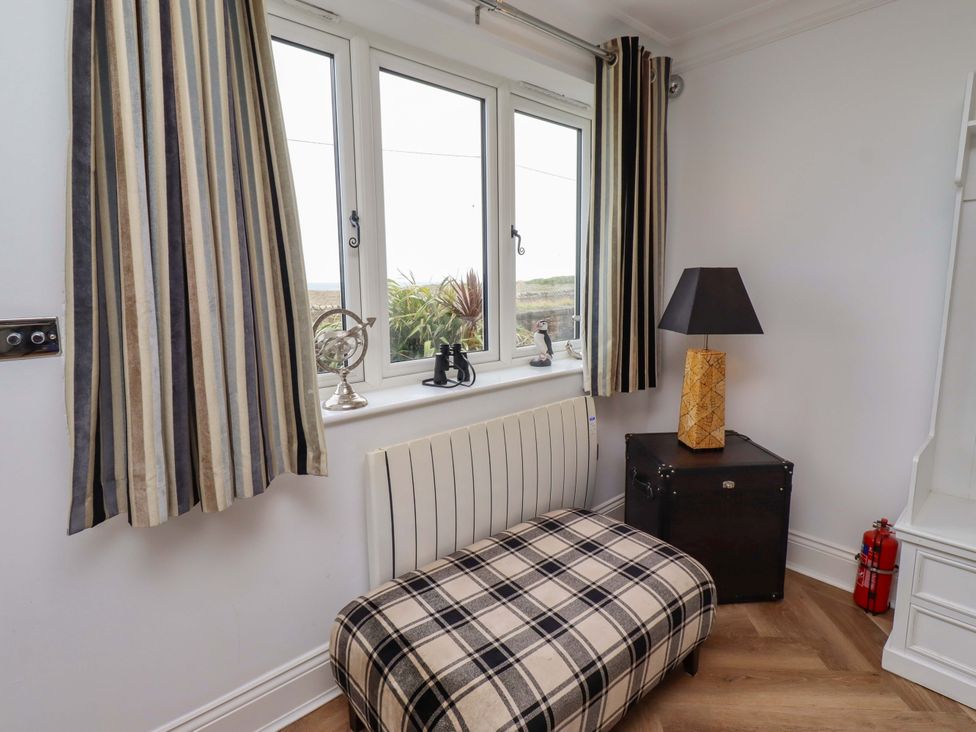 A snug area with windows and a bench at Farne Cottage Beadnell