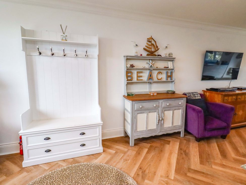 A living room with a coat rack and sideboard at Farne Cottage Beadnell
