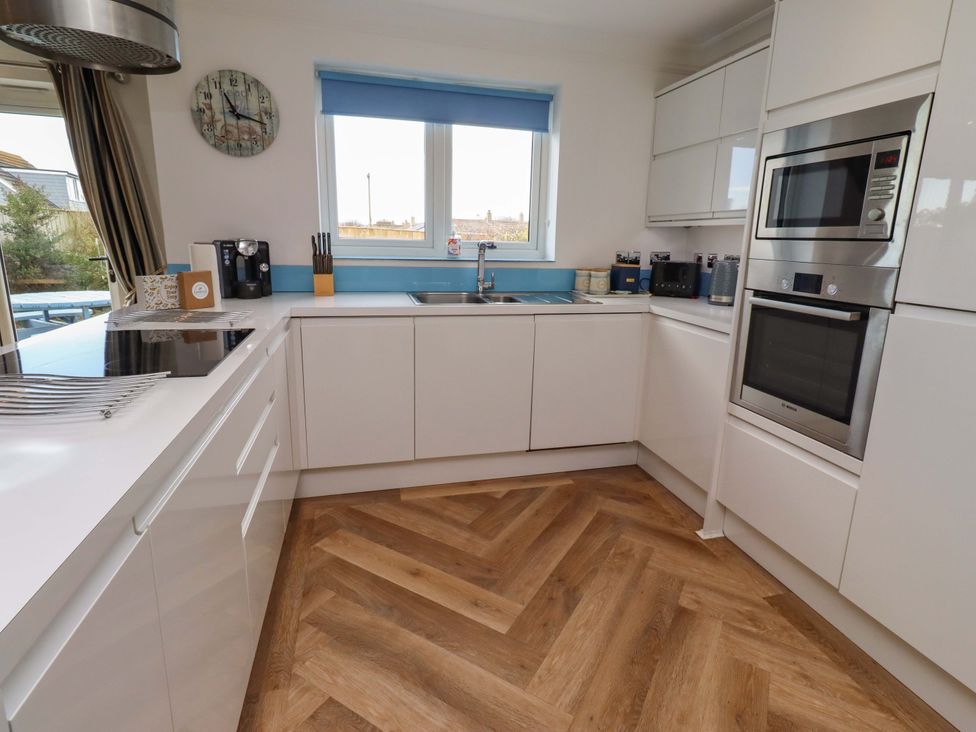 A kitchen with white cabinets and appliances at Farne Cottage Beadnell