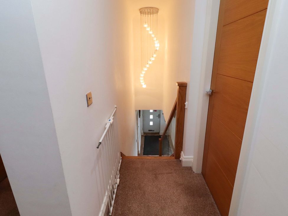 A staircase with light fixture and door at Farne Cottage Beadnell
