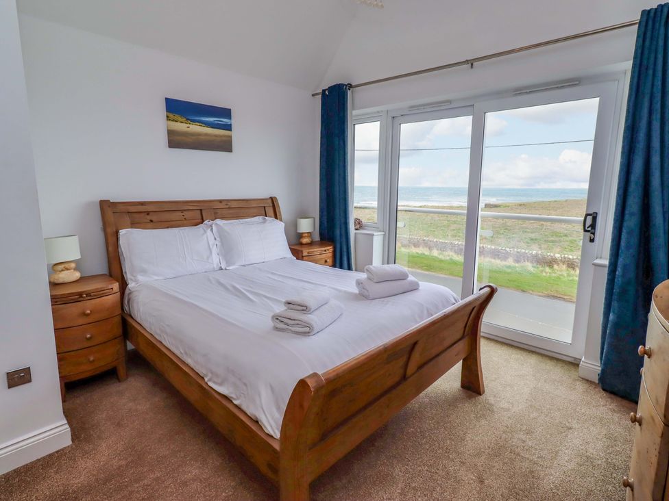 A bedroom with a double bed and a view of the outside at Farne Cottage in Beadnell