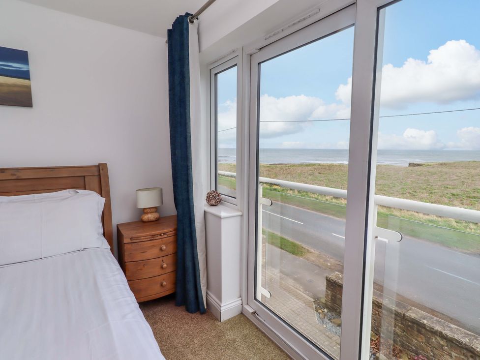 A bedroom with a bed and a window view at Farne Cottage in Beadnell