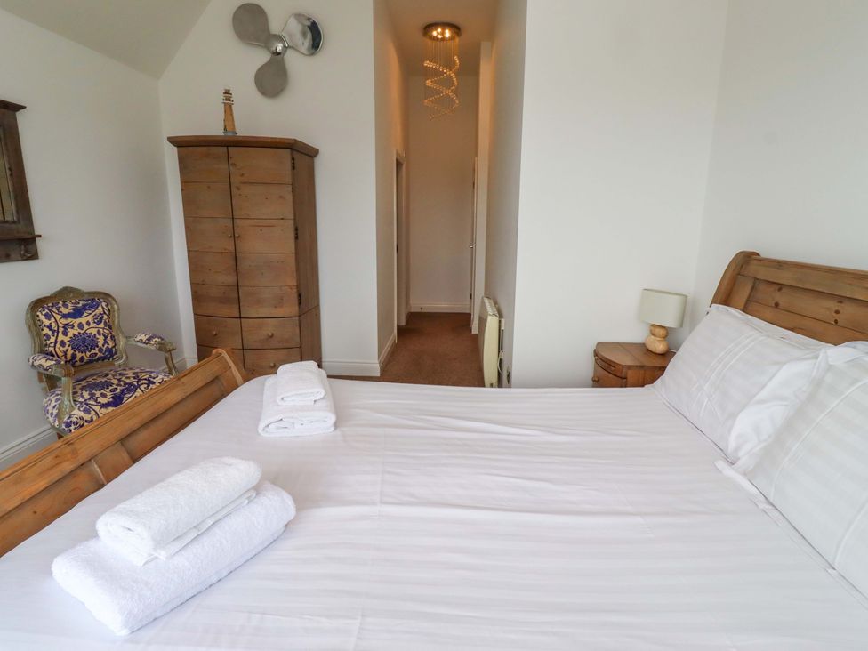 A bedroom with a bed and chair at Farne Cottage in Beadnell