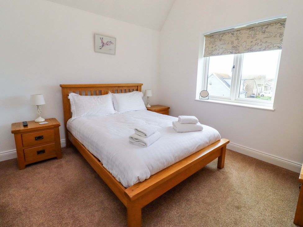 A bedroom with a bed and nightstand at Farne Cottage in Beadnell
