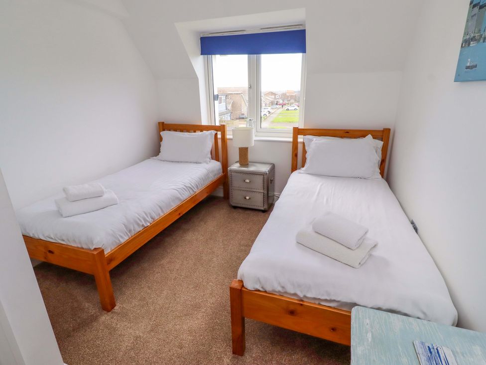 A bedroom with two single beds and a nightstand at Farne Cottage in Beadnell