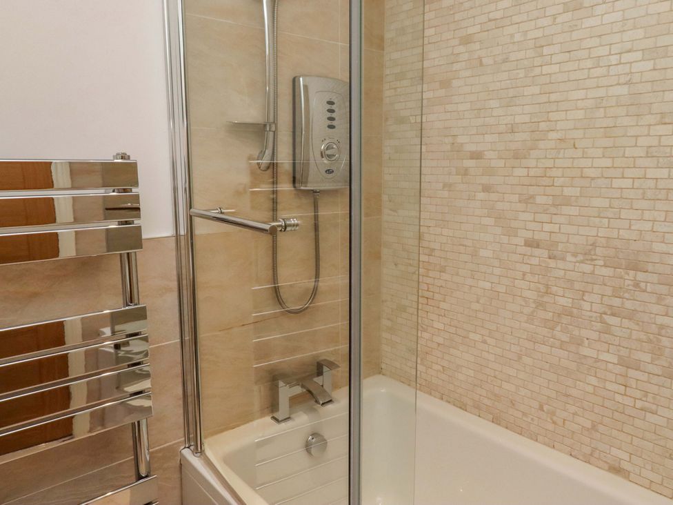 A bathroom with a shower and bathtub at Farne Cottage Beadnell