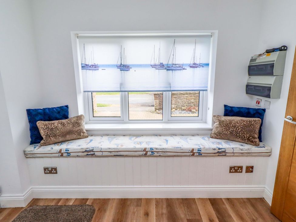 A seating area with a bench and cushions at Farne Cottage in Beadnell
