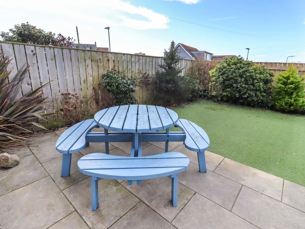 A garden with a blue table and benches at Farne Cottage Beadnell
