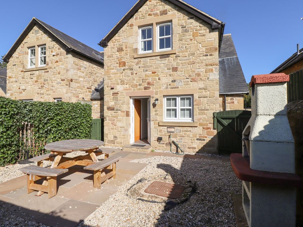 An outdoor area with a stone house and seating at Russet in Lucker