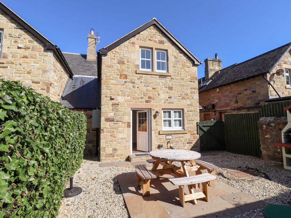 An outdoor area with a stone house and a picnic table at Russet in Lucker