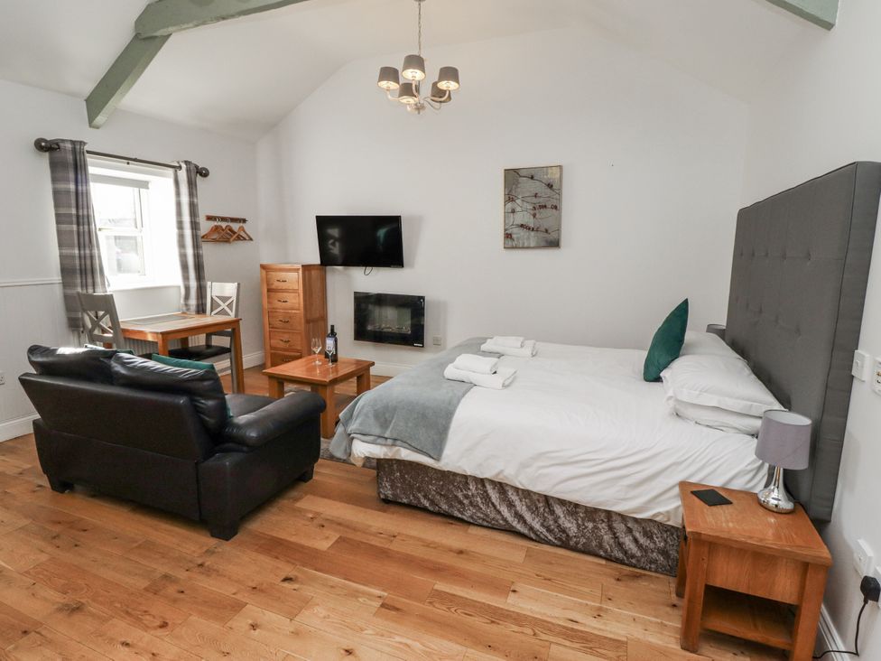A bedroom with a bed, sofa, and dining table at Avocet Cottage - Lucker Steadings Lucker