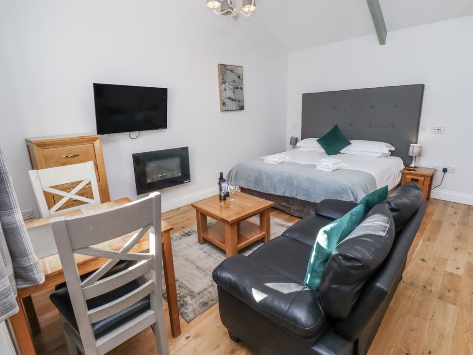 A bedroom with a bed, sofa, and TV at Avocet Cottage - Lucker Steadings Lucker