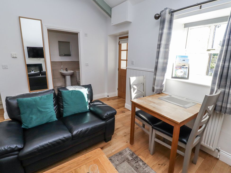 A living room with a sofa and dining table at Avocet Cottage - Lucker Steadings in Lucker