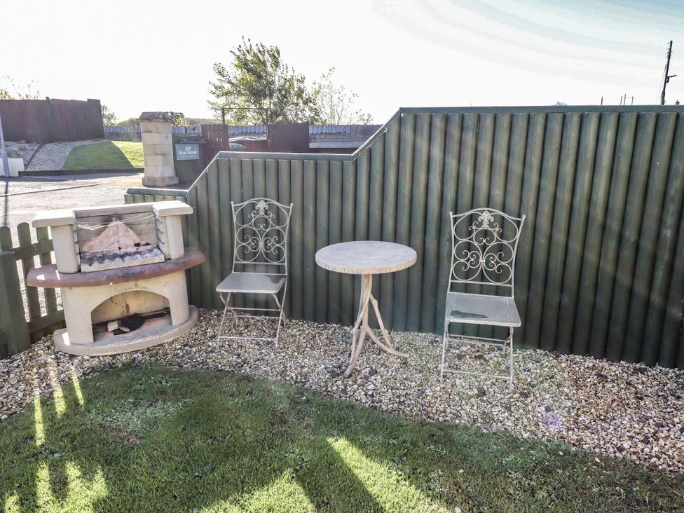 A garden with a grill, table, and chairs at Avocet Cottage - Lucker Steadings Lucker