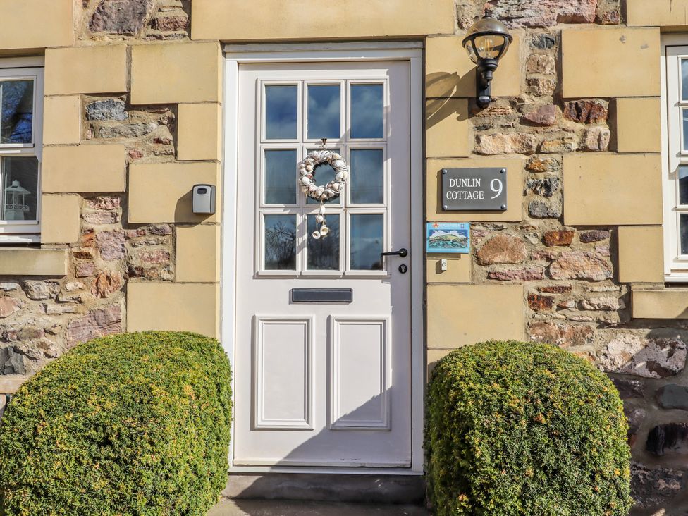 An entrance with a front door and bush at Dunlin Cottage in Bamburgh