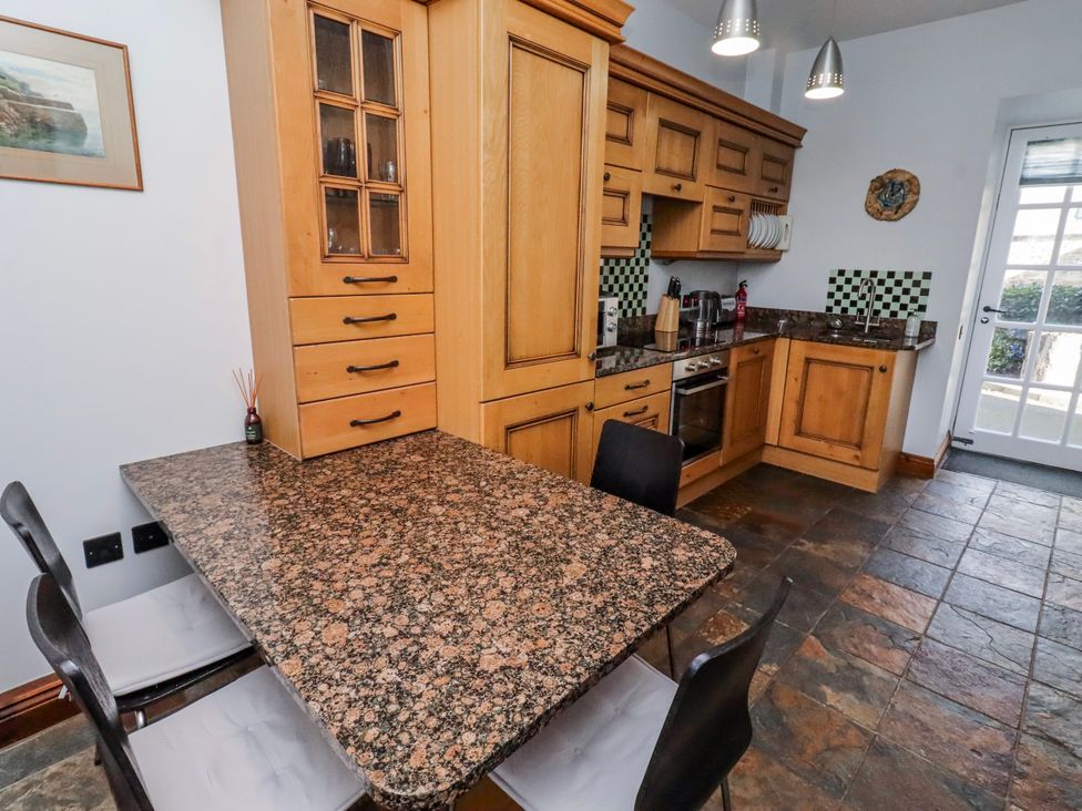 A kitchen with a granite table and wooden cabinets at No9 Budle Sands in Bamburgh