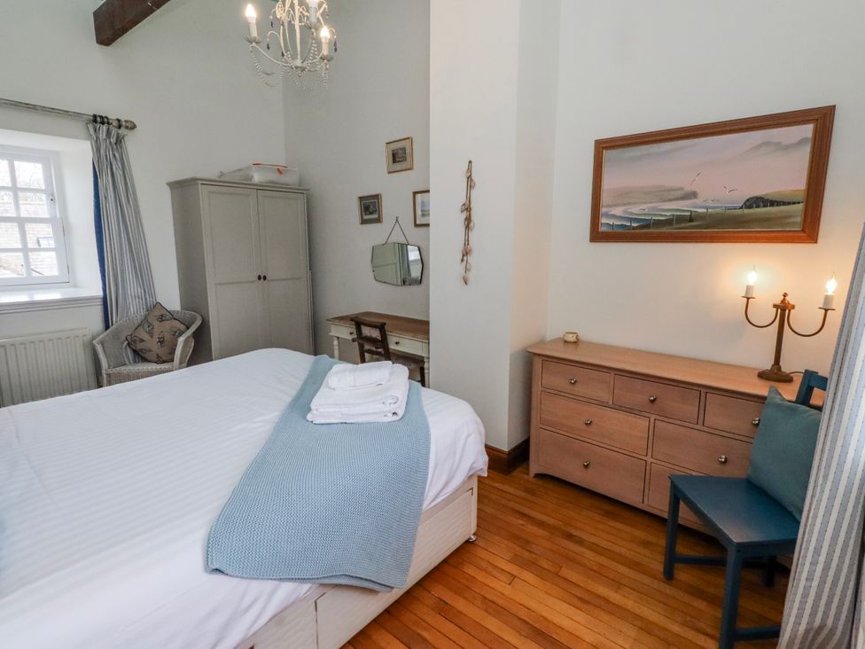 A bedroom with a bed, dresser, and chairs at No9 Budle Sands in Bamburgh