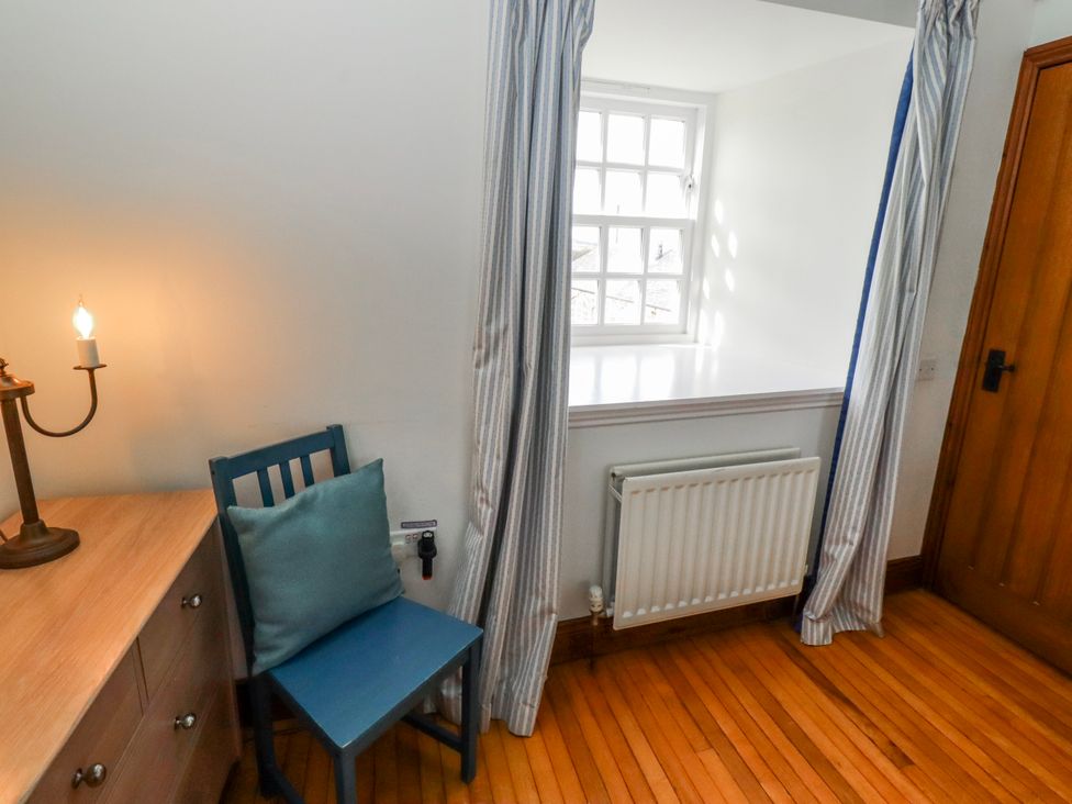 A room with a chair and a desk with a lamp at No9 Budle Sands in Bamburgh