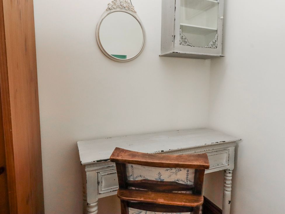 A desk and chair with a mirror and cabinet at No9 Budle Sands in Bamburgh