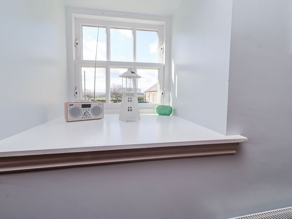 A shelf with a lamp and radio near a window at No9 Budle Sands in Bamburgh