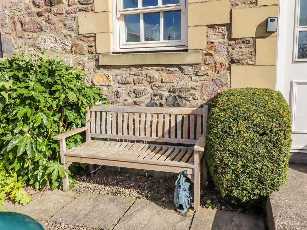 A bench beside a bush and stone wall at No9 Budle Sands in Bamburgh