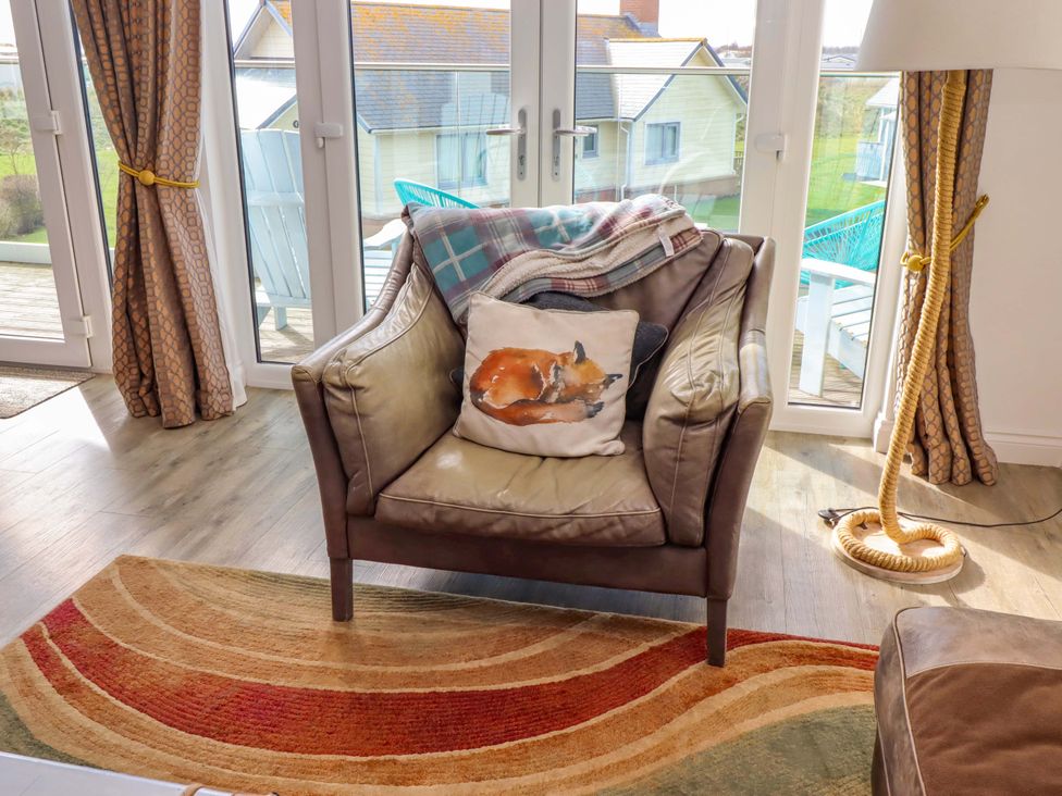 A living room with an armchair and blanket at Spindrifter in Beadnell