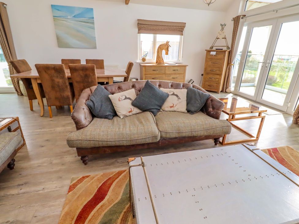 A living room with a sofa and dining area at Spindrifter in Beadnell